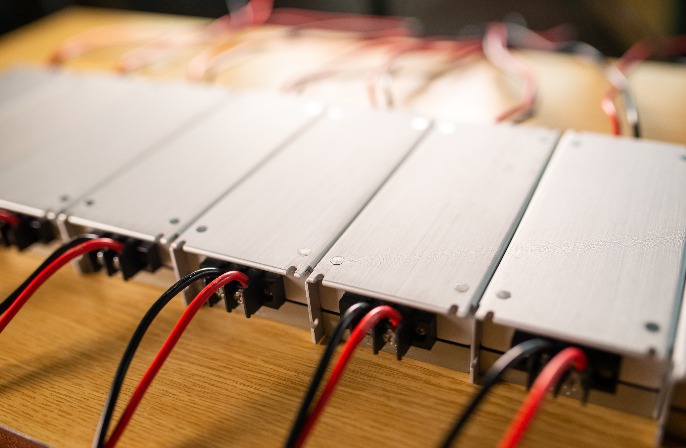 Row of aluminum power electronics modules connected with red and black wires