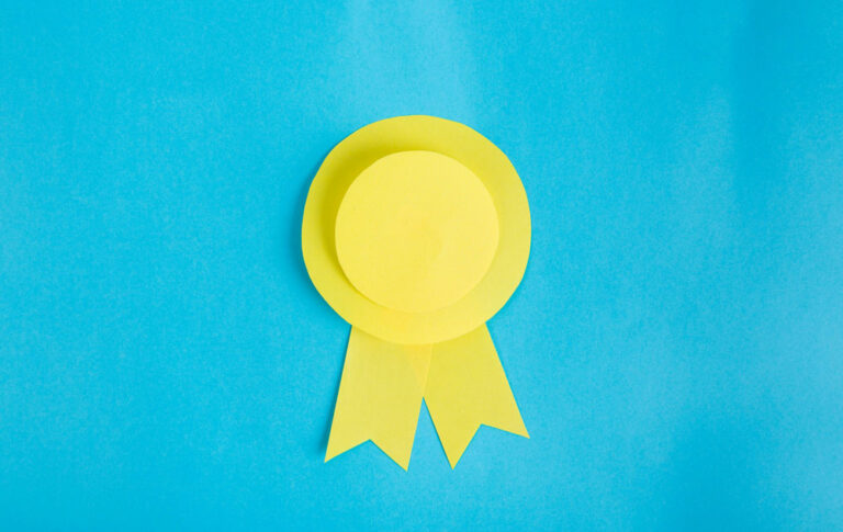 Yellow paper award rosette ribbon on a bright blue background