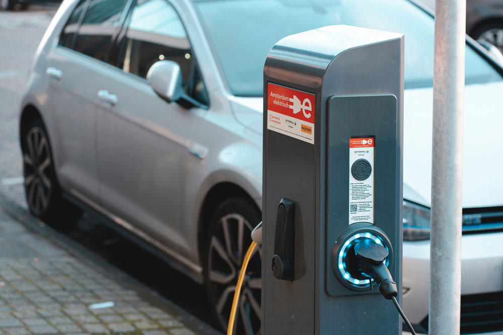 Electric car plugged into an Amsterdam street charging station with glowing connector