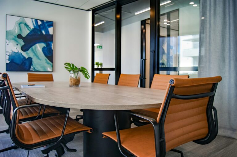 Modern conference room with a wooden oval table and tan leather chairs