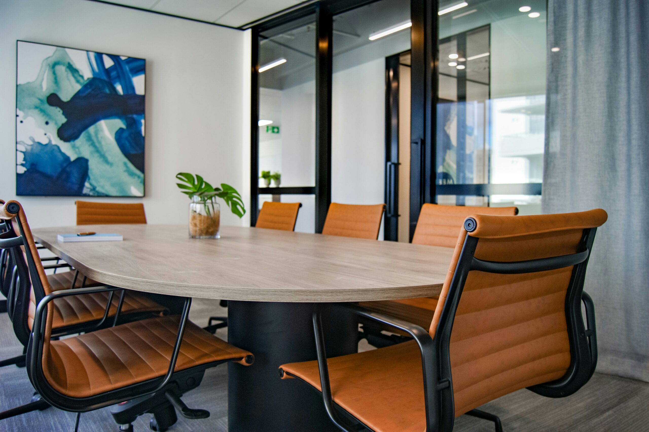 Modern conference room with a wooden oval table and tan leather chairs