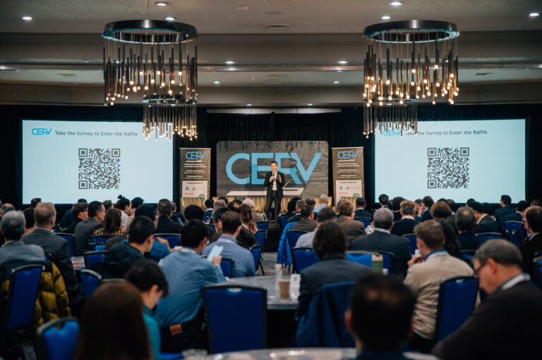 Speaker addressing a seated audience at the CERV conference with QR code survey screens