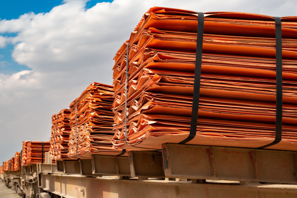 Stacked sheets of refined copper cathodes strapped onto a rail car under a blue sky
