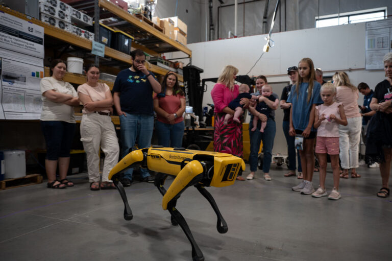 Boston Dynamics yellow Spot robot dog demonstrated to onlookers in an engineering lab