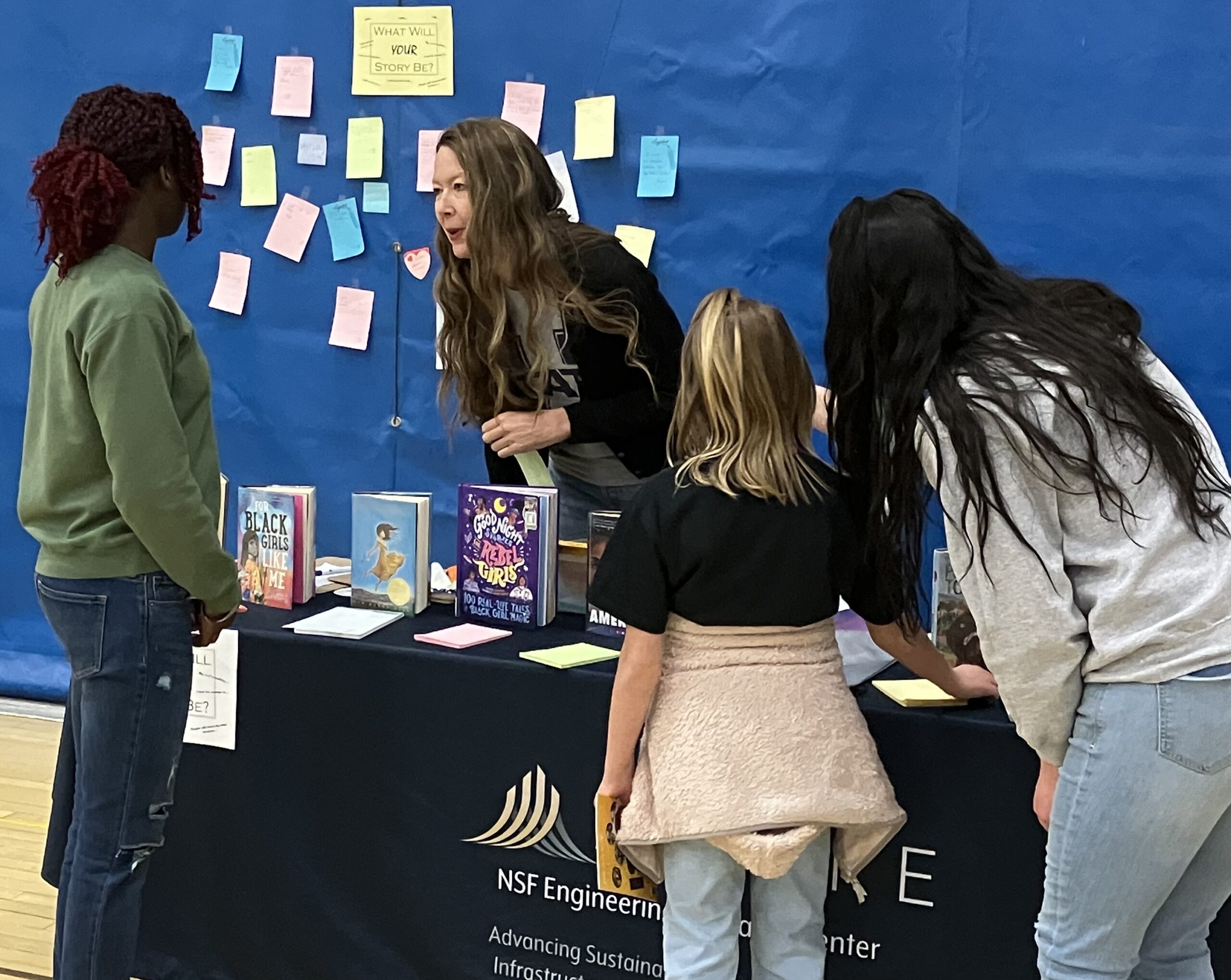 Woman engaging students at an NSF Engineering Research Center book display table at an outreach event
