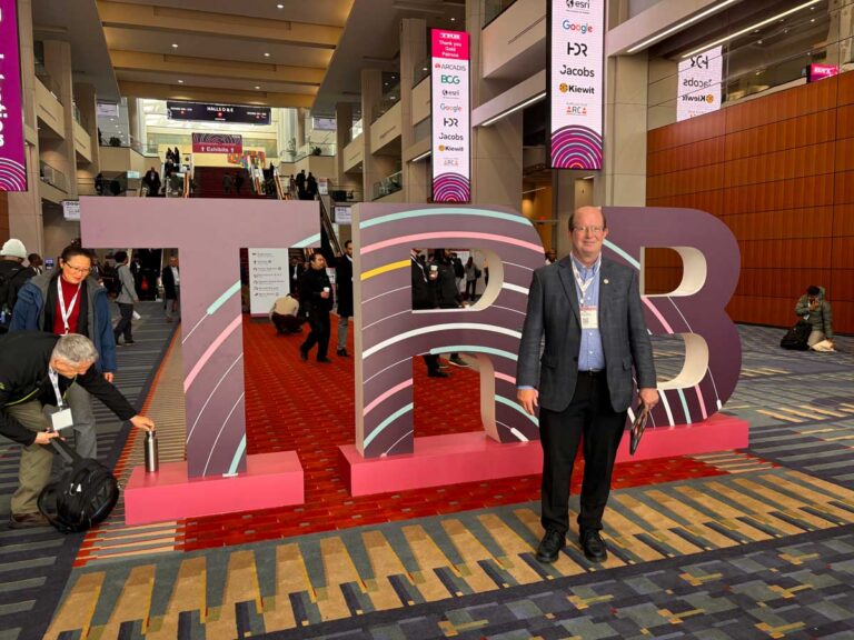 Man in a suit standing in front of large illuminated TRB letter sculpture at the conference