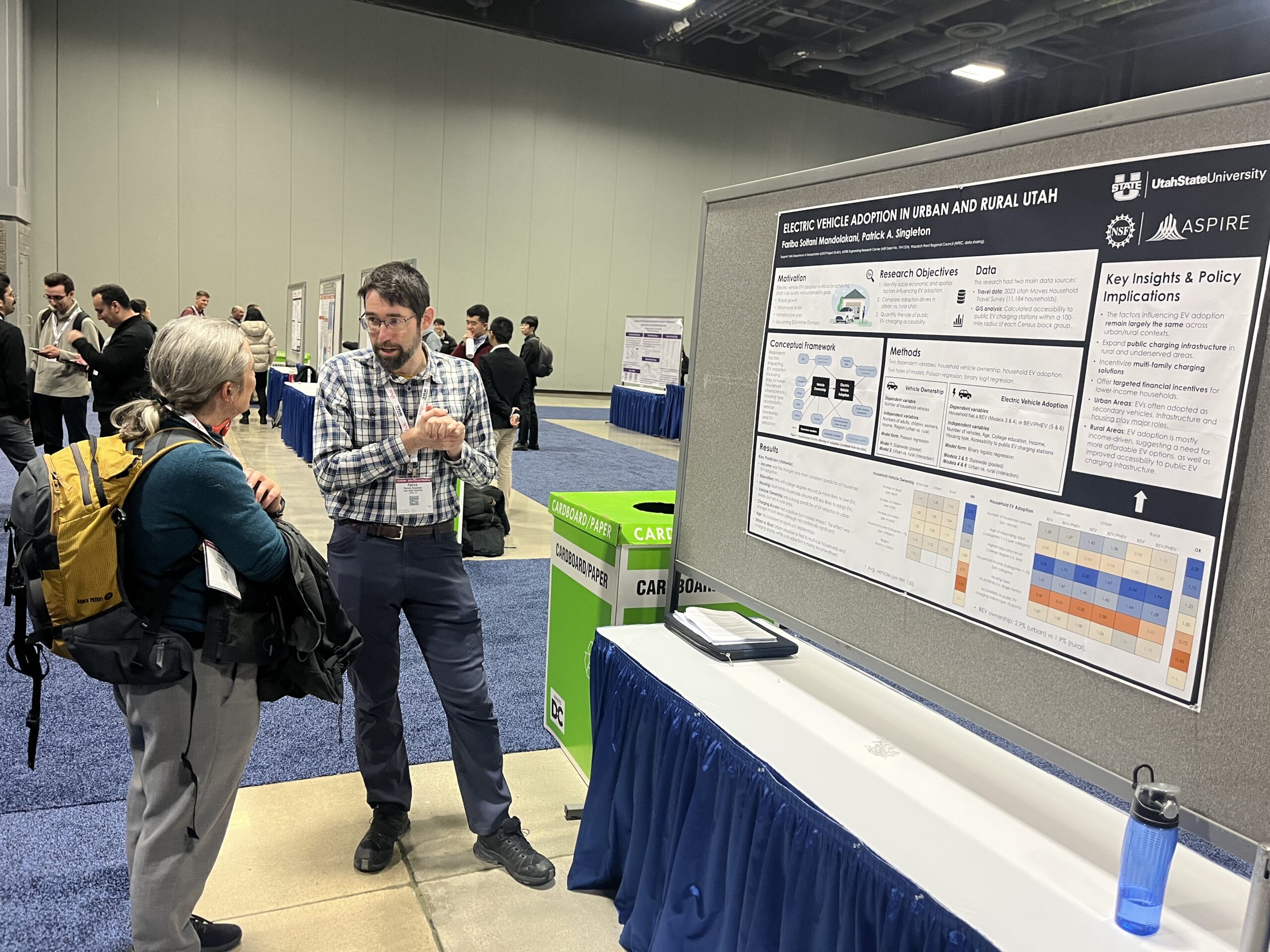 Researcher discussing his EV adoption in urban and rural Utah poster with an attendee at a conference