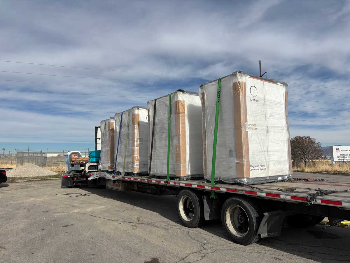 Shrink-wrapped Sonnen megawatt power conversion battery units secured on a flatbed truck trailer